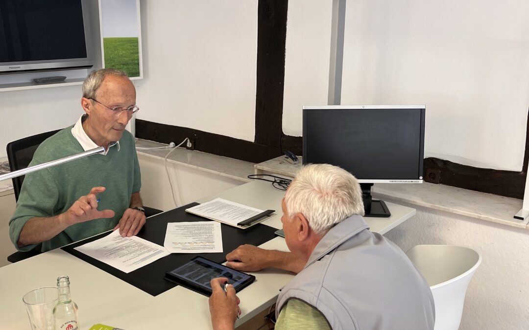 !B Energieberater sitzt am Tisch einem Kunden gegenüber und erklärt